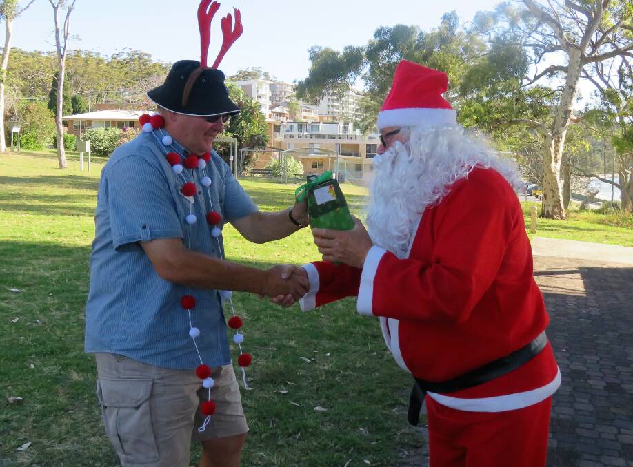 FRIVOLITY: Santa hands a gift to David Wilson at the annual Probus Christmas Nibbles in the Park. Picture: Supplied