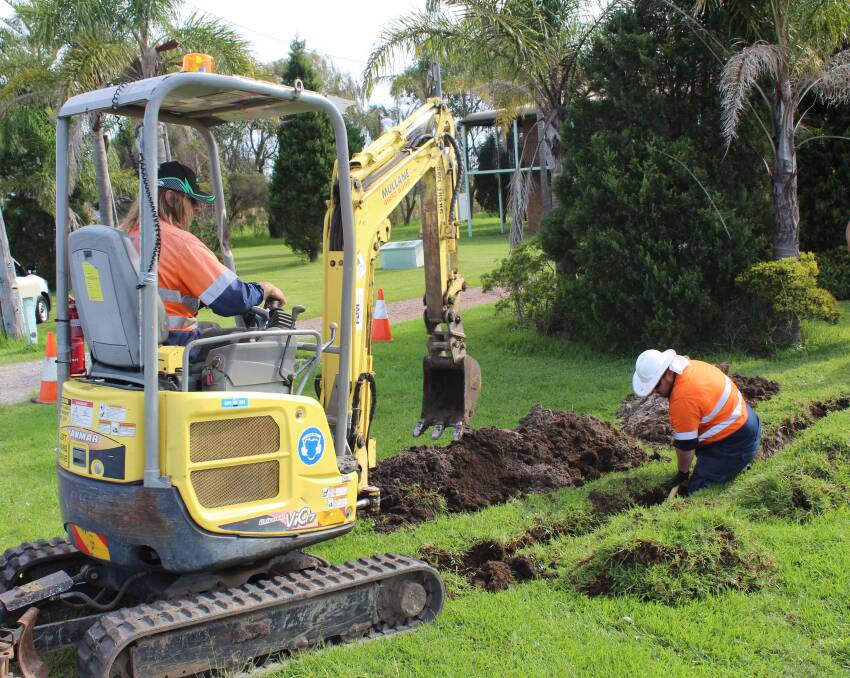 HARD AT IT: Contractors work to connect a home to town water in the Williamtown red zone.