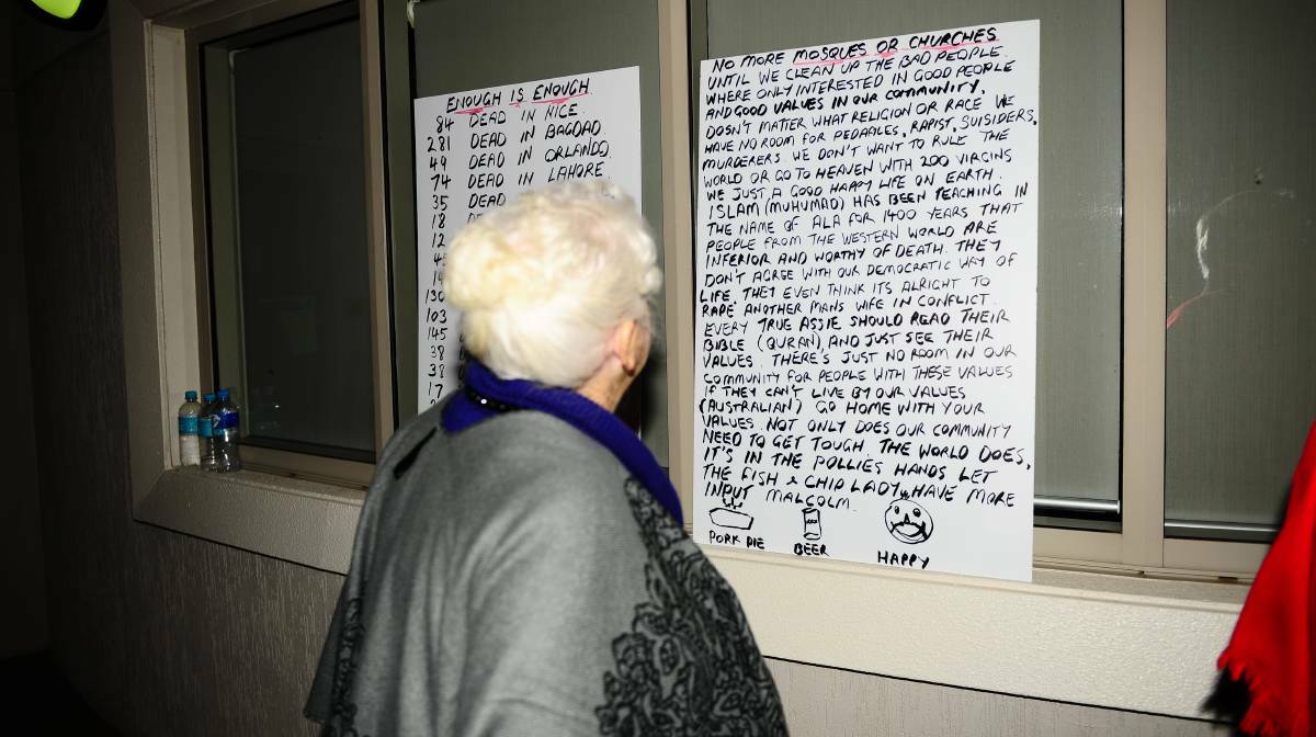 A Cessnock councillor reads an anti-mosque poster outside the council chambers on Wednesday night. Picture: Sage Swinton