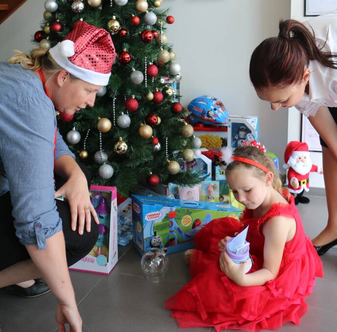JOY: Debbie Jones with Alyssa, 4, and Marlene Borg from Nelson Bay Real Estate, taking a peek at the gifts donated so far.
