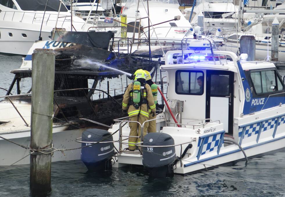 DESTROYED: Fire and Rescue NSW firefighters on board a water police launch extinguish a fire near d'Albora Marinas, Nelson Bay, on May 19. Picture: Fire and Rescue NSW