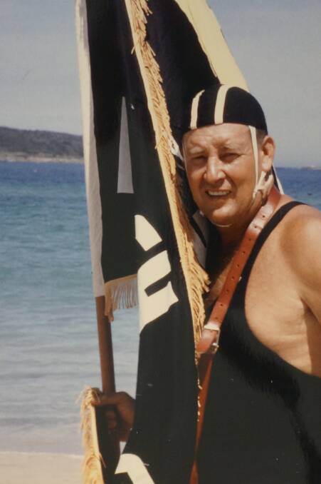 ROLE MODEL: Long-time Fingal Bay resident Norm Karlson with a flag from the suburb's surf club, which he helped start.