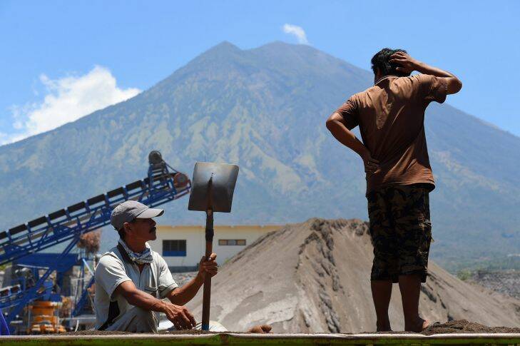 Inside the exclusion zone, day labourers take a break from shovelling sand and gravel from a truck at the PT Bhale Dana mine in Kubu area at the base of Mount Agung in Bali, Indonesia.  27th of September, 2017. Photo: Kate Geraghty