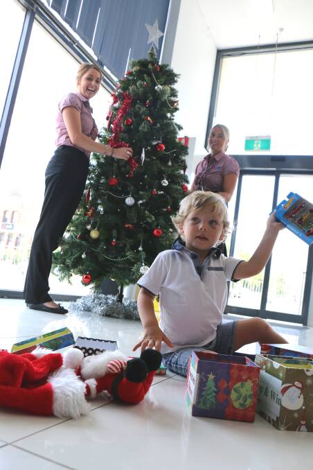 LOOK MUM: Kaige Ward, 2, opens gifts while Olivia Higgins and Kate Fuller from Dowling Raymond Terrace dress the tree.