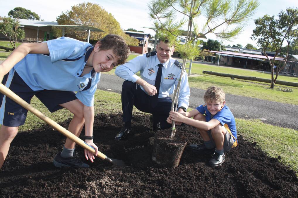 HELPING HANDS: SQNLDR Maurice Hall and his sons Mitchell (year 7) and Ben (year 3) plant the lone pine sapling at Tomaree High School.