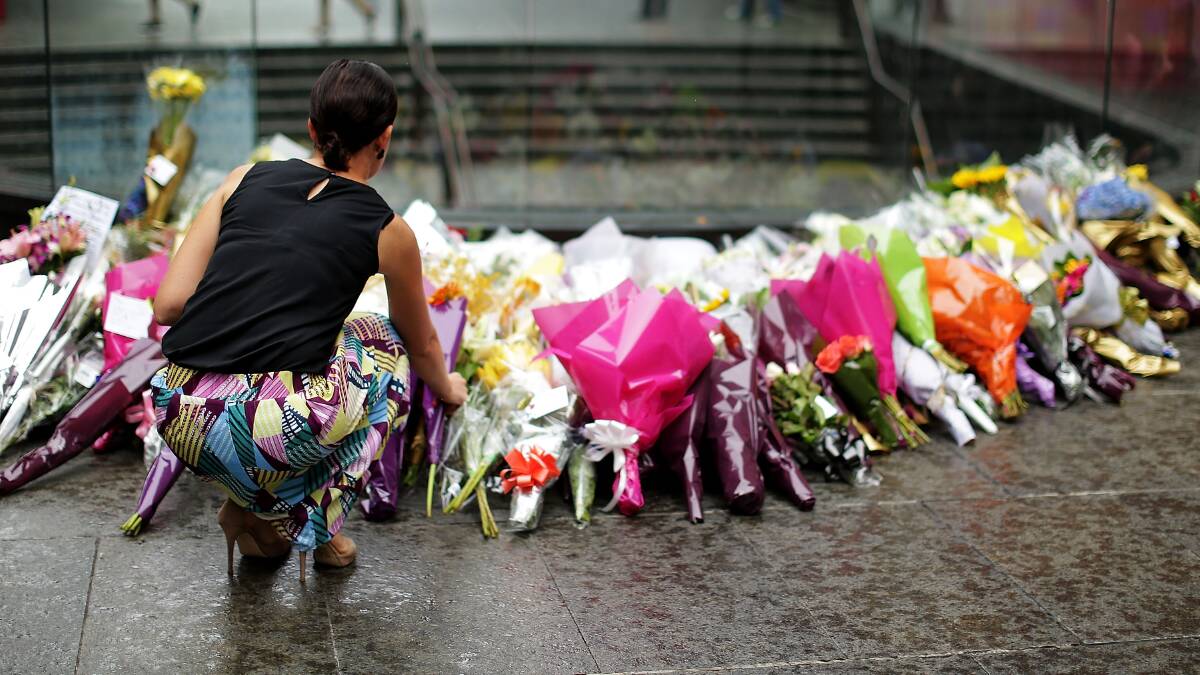 A woman adds a floral tribute to the hundreds that have been left in Martin Place. Photo: Getty Images. 