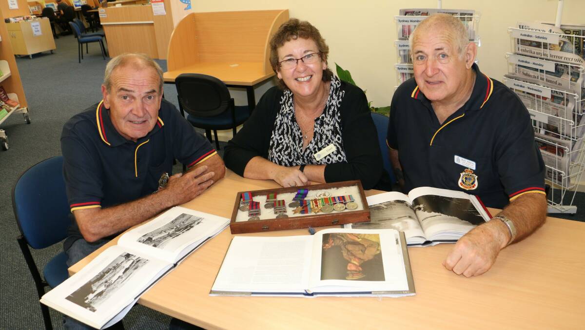VISION PRAISED: Bruce Everitt, Carol Johnson and Ray Prigg at Tea Gardens Library looking at artefacts in the Anzac exhibition. Picture by Stephen Wark.