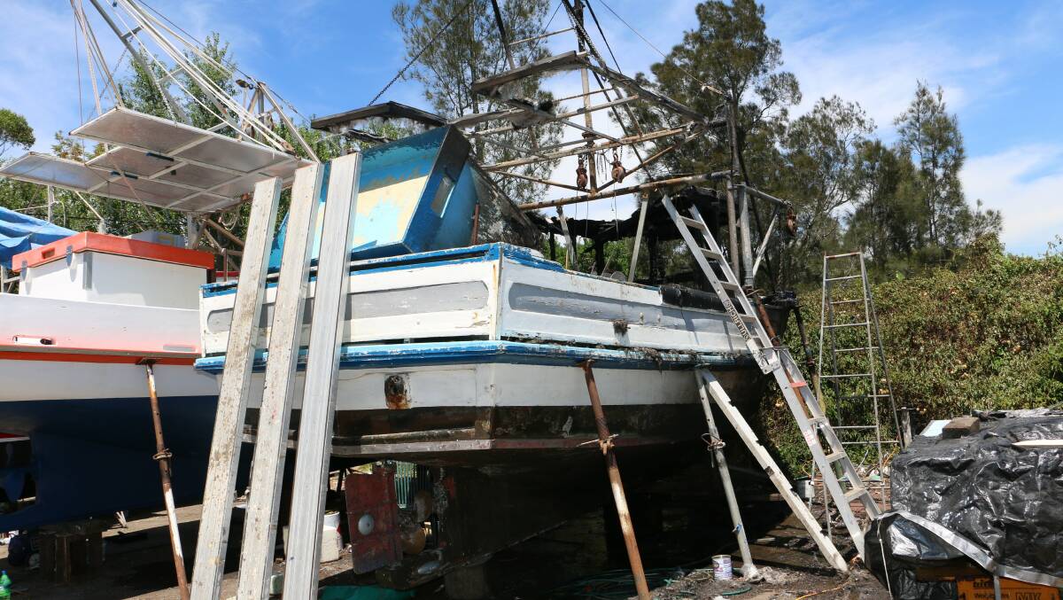 A boat dry docked in Raymond Terrace has been destroyed and other damaged in a fire on Wednesday night. Pictures: Stephen Wark.