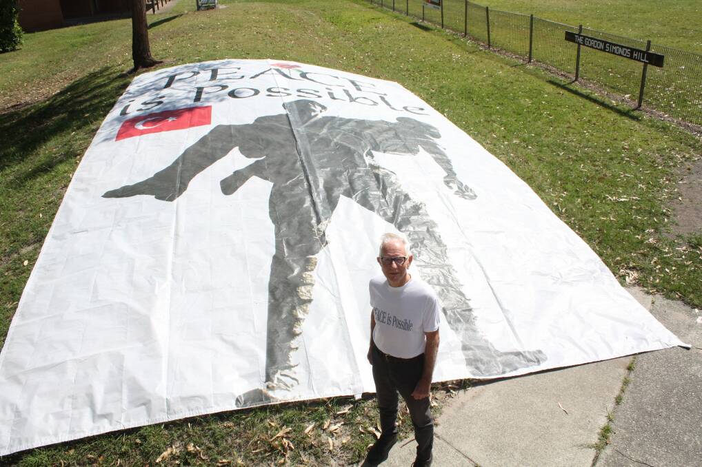 ON MESSAGE: Norman Ainsworth standing with his Peace is Possible banner at Bill Strong Oval, Nelson Bay.
