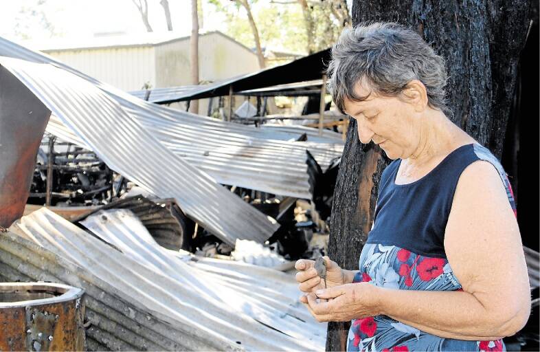 HEARTBREAK: Pam la Frentz, holds her husband's dog tags in the ashes of her backyard. Picture: Michael McGowan