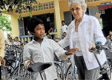 WAY TO GO: Jan Holbert hands a bike to a Cambodian youth.
