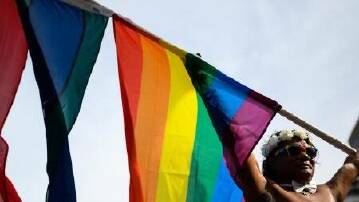 Woman holds a rainbow flag over her head. Picture AAP image