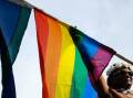 Woman holds a rainbow flag over her head. Picture AAP image