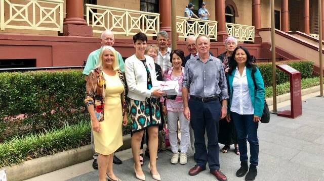 HOPEFUL: Port Stephens MP Kate Washington with members of the Mambo Wanda Wetlands Conservation Group and the petition before the debate. Picture: Supplied
