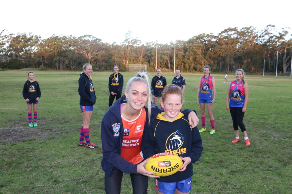 GIANT: Pippa Smyth, who plays in the AFLW, with Nelson Bay Junior AFL Club's Olivia Gray, 9, at a coaching clinic on Monday.