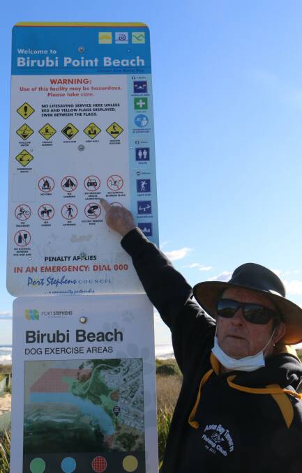 OPEN UP: Anna Bay Fishing Club member Paul Holliday points to the Robinson Reserve sign which says: 'No vehicles unless launching'.