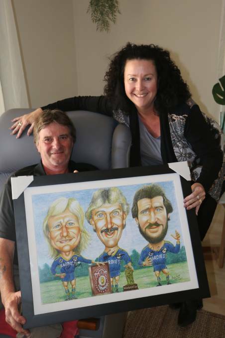 Steve Lingard in 2018, pictured with raffle organiser Meagan Harding and the prize, a caricature of three Eels greats Peter Sterling, Brett Kenny and Ray Price.