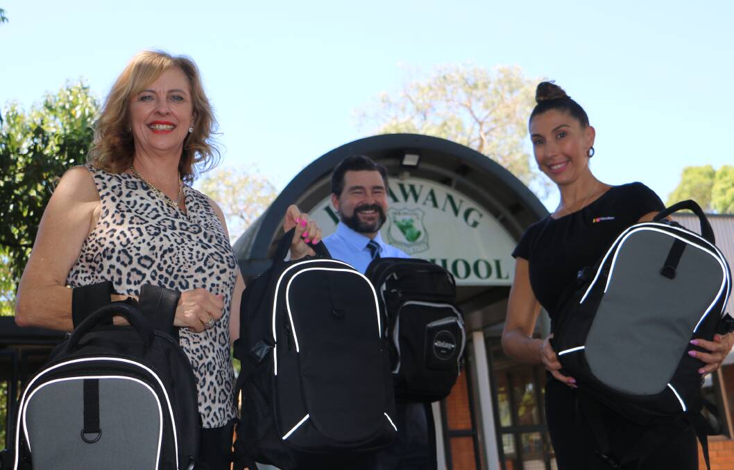 DONATION: From left: Tracy Jonovski, Irrawang High principal Paul Baxter and Melissa Parkinson with some of the 250 backpacks to be distributed to local school children for the start of the school year.