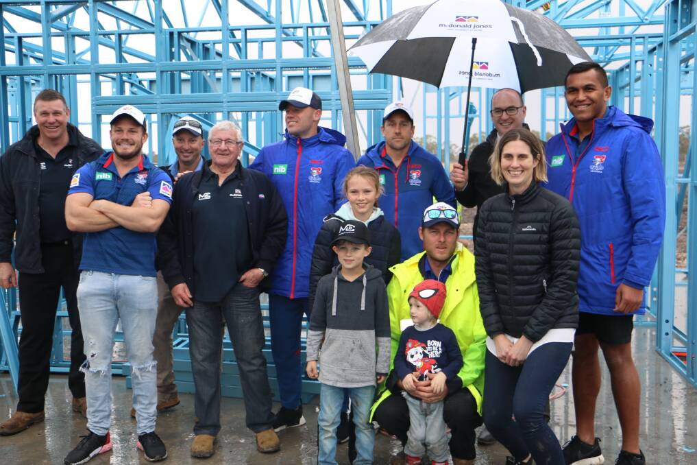 BUILD FOR CURE: Knights players with construction representatives, parents Brodie Dongean and Nick Ball with children Nixon, 3, Ashlee, 7, and Lachlan, 10.