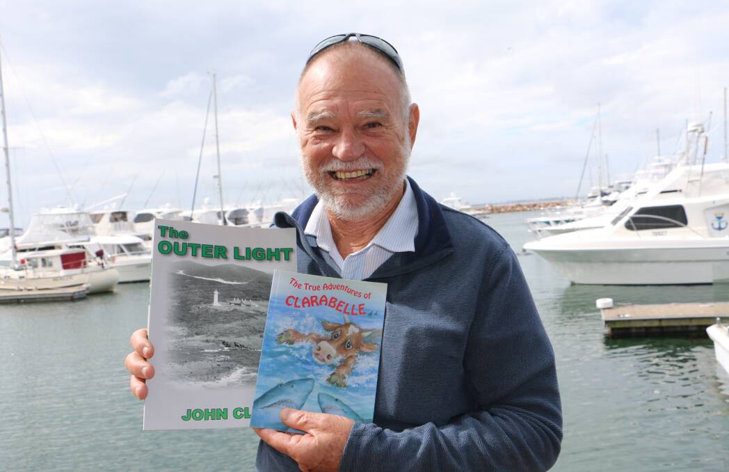 AUTHOR: John Clarke promoting a couple of his books against the backdrop of the Nelson Bay marina.