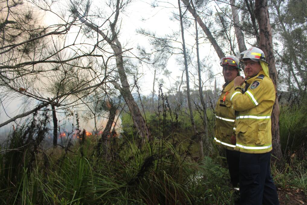 FIRE WATCH: Two firefighters keep a close eye on the controlled fire just off Foreshore Drive at Salamander Bay on Tuesday morning.