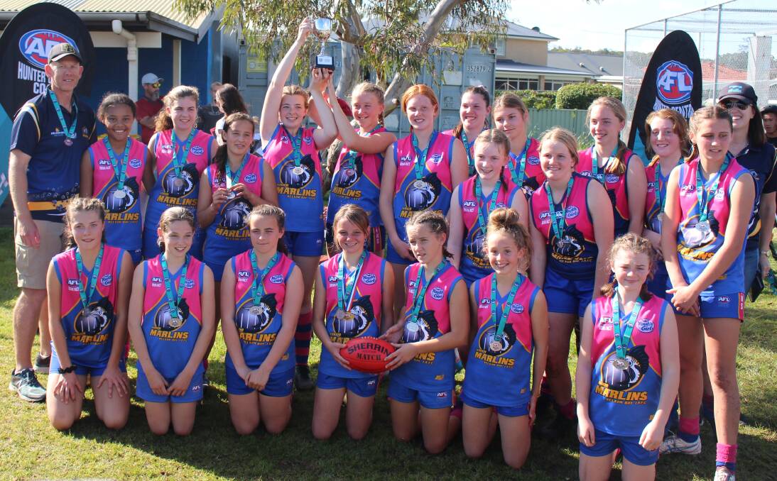 HAT-TRICK: The Nelson Bay AFL Marlins grand final winning under 13 girls team raise the trophy last Sunday.
