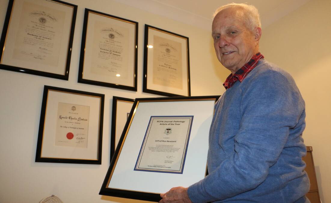 Professor Ron Newland with his framed certificate at his Fingal Bay home.