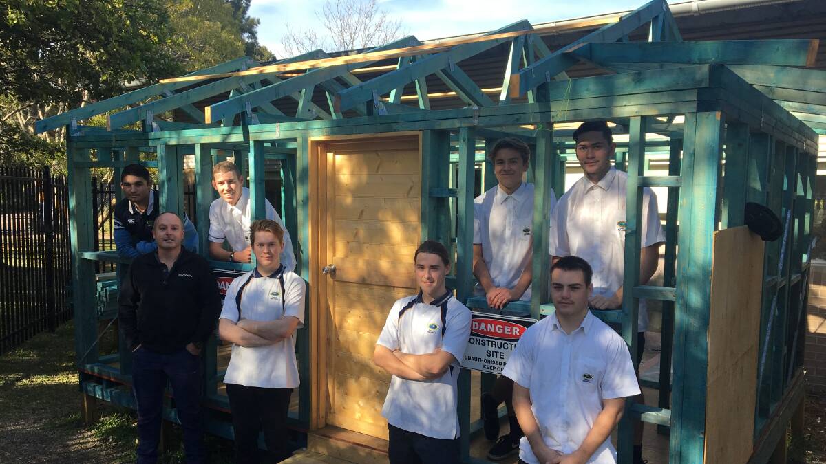 HOUSE PROUD: The Tomaree High School Year 12 construction class with teacher Adrian Crew and the mini house. Picture: Supplied