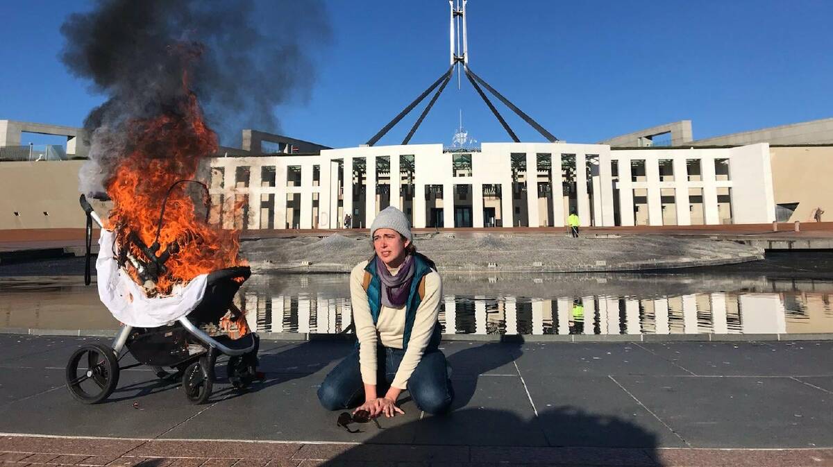 Extinction Rebelion member Violet Coco besides a burning pram outside Parliament House. Picture: Supplied