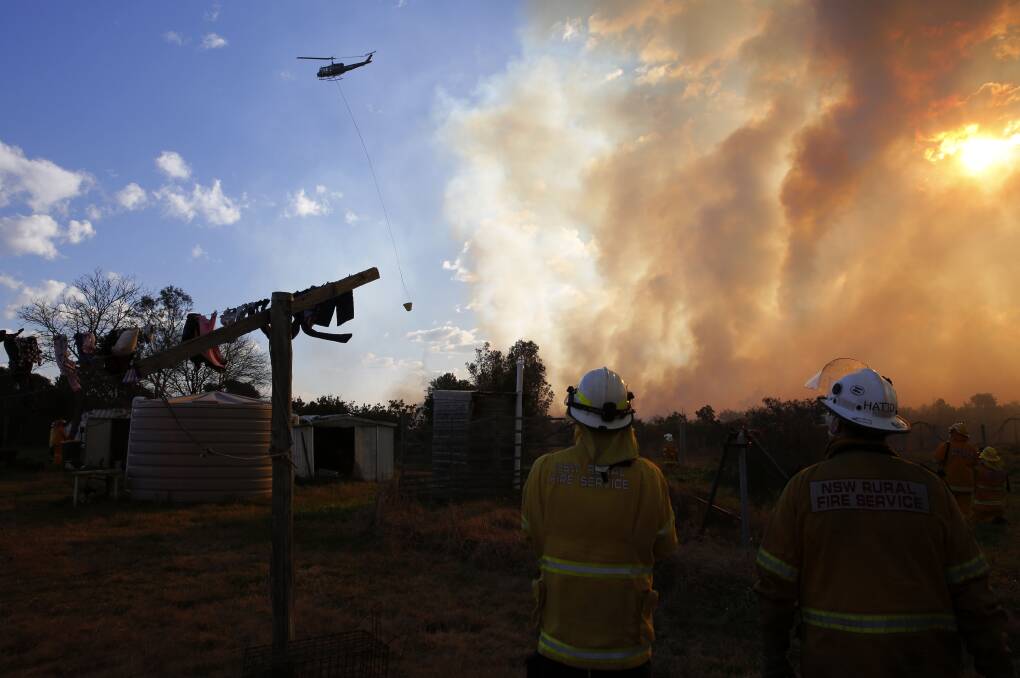 CLEANING UP: Firefighters at Salt Ash watch a water-bombing helicopter fly past. Picture: Darren Pateman, AAP