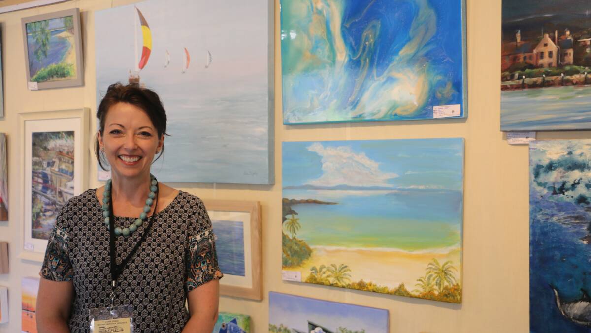 SUMMER: Cory Acorn, Port Stephens Community Art Centre gallery director, standing next to artworks featured in the current exhibition 'Summertime'. Picture: Kia Woodmore