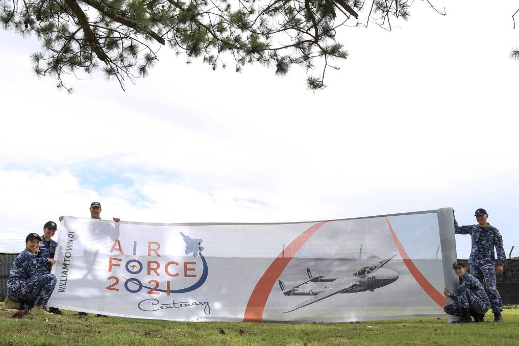Williamtown RAAF Base personnel unfurling one of the 50m long centenary banners, which will be hung outside the base.