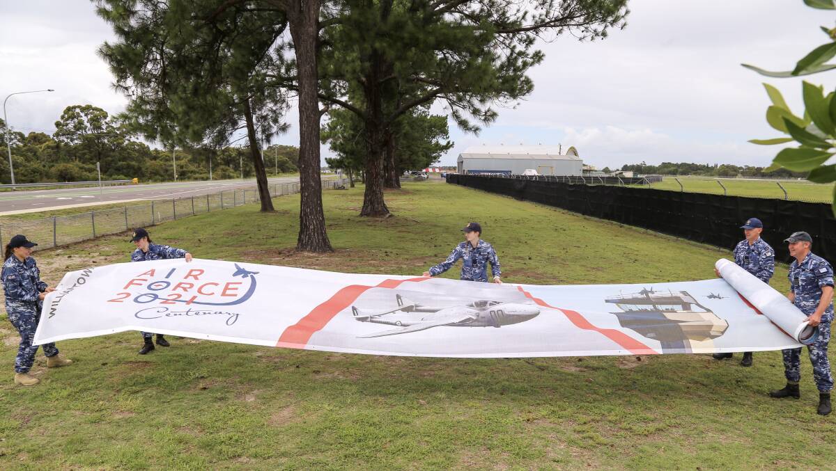 Williamtown RAAF Base personnel unfurling one of the centenary banners.