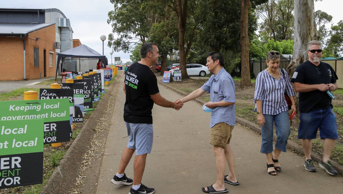 Incumbent Port Stephens mayor Ryan Palmer meeting a voter at Irrawang High School in Raymond Terrace on Saturday morning.