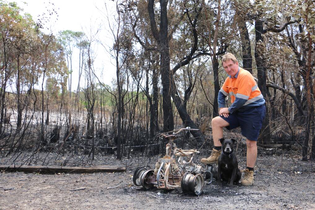 ASHEN: Des Maslen and his dog, Rex, next to a quad bike that was claimed by the fire at his Williamtown property on Saturday. Picture: Ellie-Marie Watts