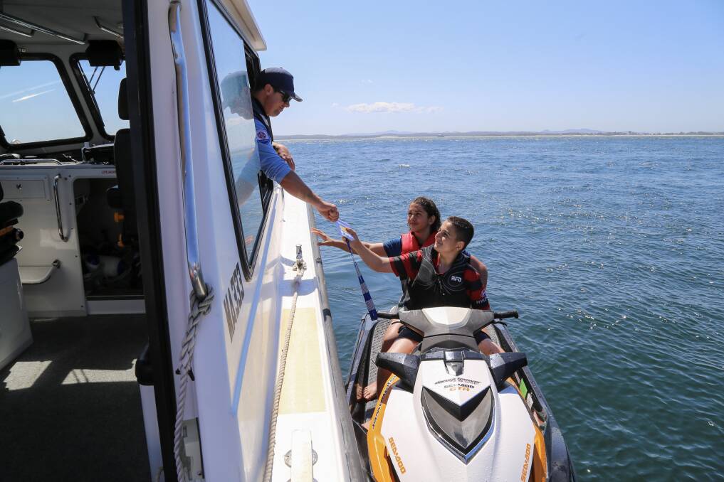 CHAT AND CHECK: NSW Maritime Boating Safety Officer Mick Cleland talking with two teens on a jet ski at Little Beach on Sunday. 