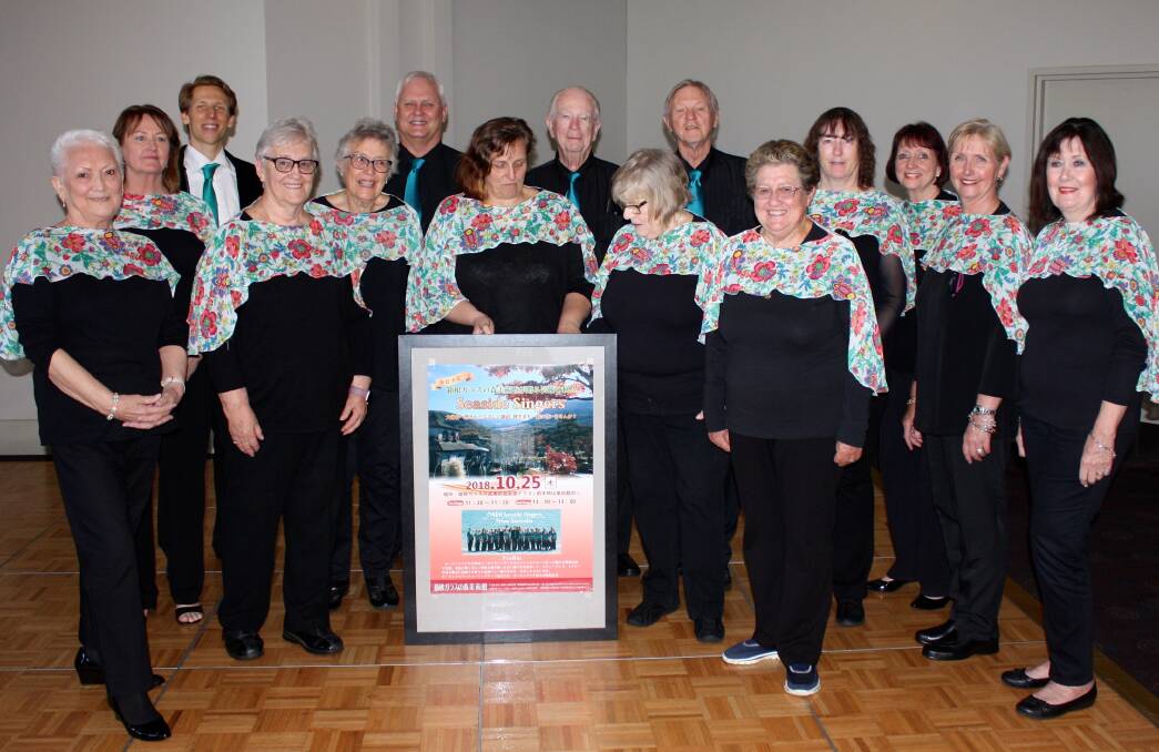 The Japan bound Seaside Singers with a poster for their Hakone Venetian Glass Museum performance (from left) Hazel Basnett, Helen Jackson, Ellery Durrant (music director), Jeanette Antrum, Helen Revell, Wayne Livermore, Ria Quayle, Peter Cowling, Cathy McWilliam, Colin Murdoch, Carole Delaney, Nerida O'Shea, Ellen Robson, Sabine Dow and Delohrey Olsson.