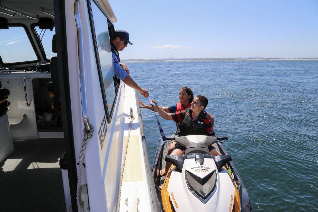 NSW Maritime Boating Safety Officer Mick Cleland talking with two teens on a jet ski at Little Beach in October 2020. Picture: Ellie-Marie Watts