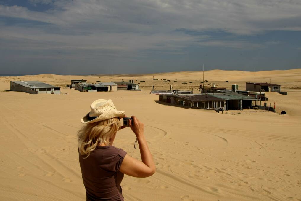 A woman takes a photo of Tin City. Tin City began in the early 1900’s when two tin shacks were built for shipwreck survivors. During the great depression of the 1930’s, Tin City grew to over 36 huts. Eleven of these huts still stand today. Tin City is the last legal squatter settlement in Australia. It is located within the Stockton sand dunes.