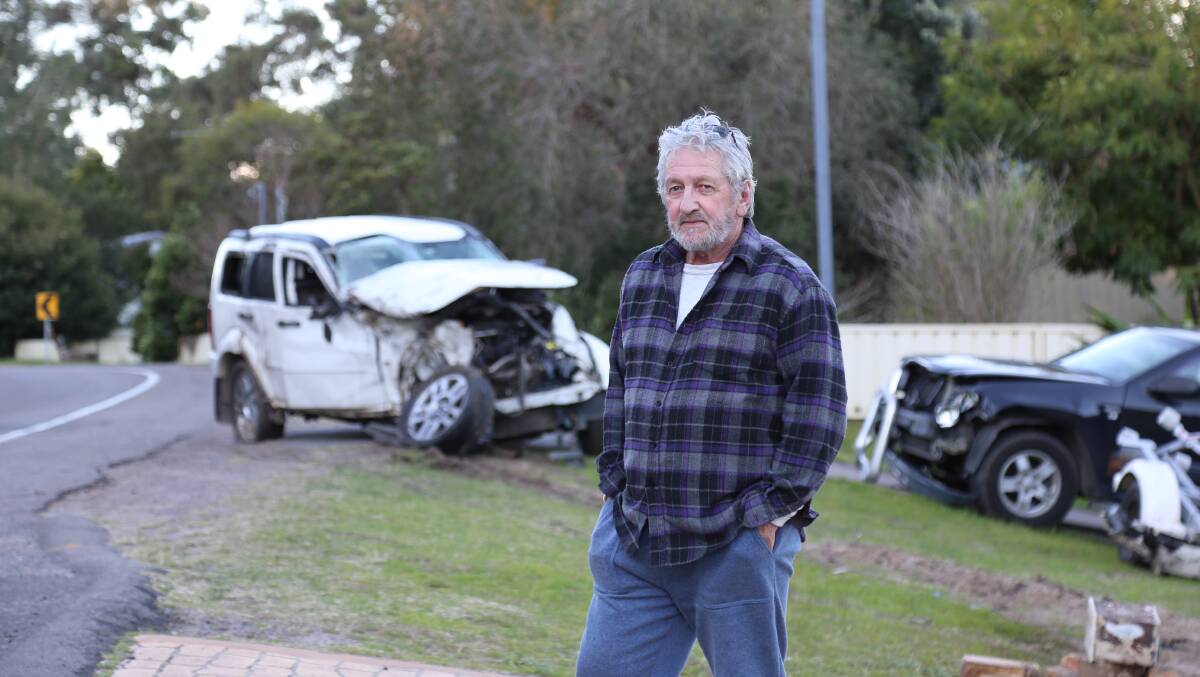 DANGEROUS: Paul Fairhall is calling for speed cameras to be installed along Lemon Tree Passage Road near a bend that was scene to an accident on Sunday. Behind him are cars damaged in the crash.