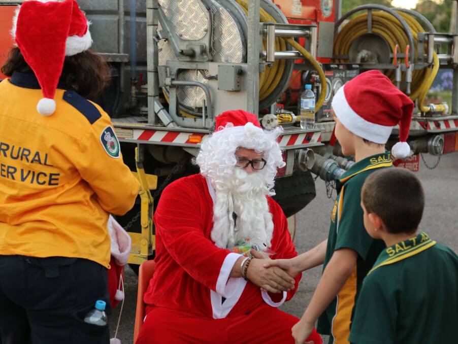 Williamtown/Salt Ash Rural Fire Brigade with Santa and school children in 2018. The Santa lolly run returns on Saturday.