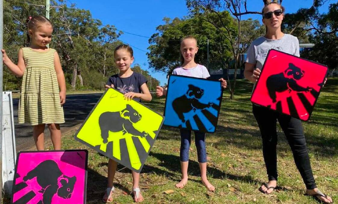 HOMEMADE SIGNS: Casey Freeman and her three children - Isabella, aged 8, Ruby, 6, and three-year-old Scarlett with the signs they have posted on the Tomaree peninsula.
