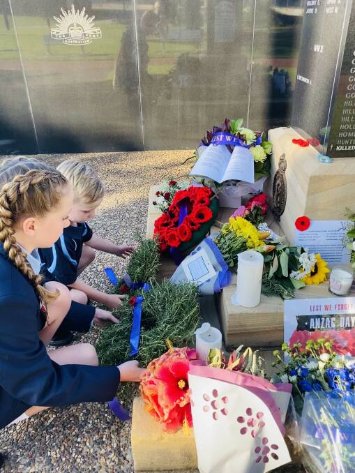 Anna Bay siblings Rhylin, 5, and Emily Green, 11, took time out while on their daily walk on Saturday to lay home made rosemary wreaths at the Nelson Bay war memorial. Picture: Zoe Green