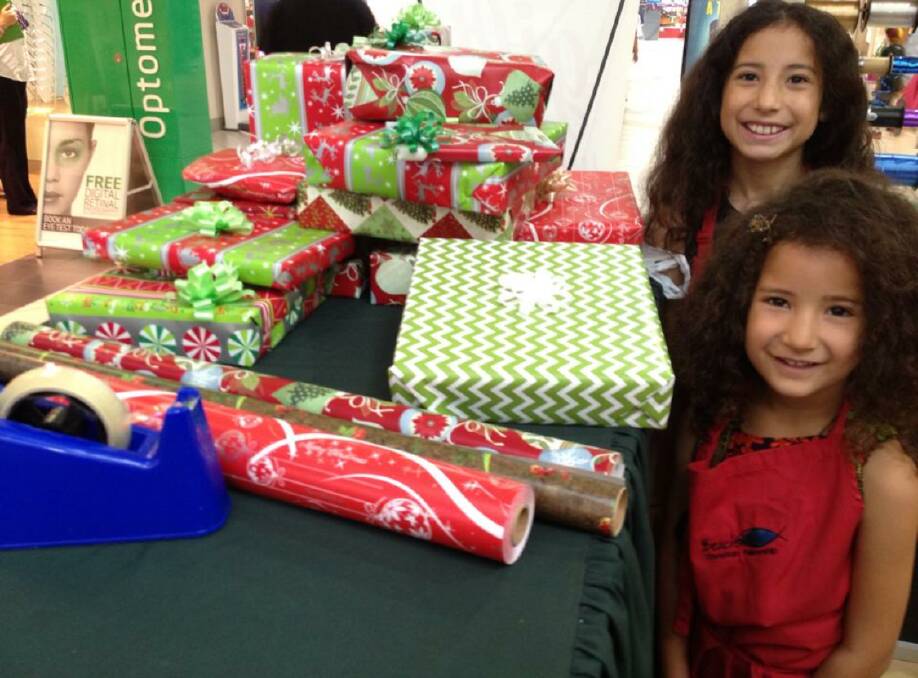 SPREAD JOY: Emily Brill, 14, and Katie Brill, 9, at the Christmas gift wrapping station in Salamander Bay Square last year. The pair are experienced gift wrappers. 