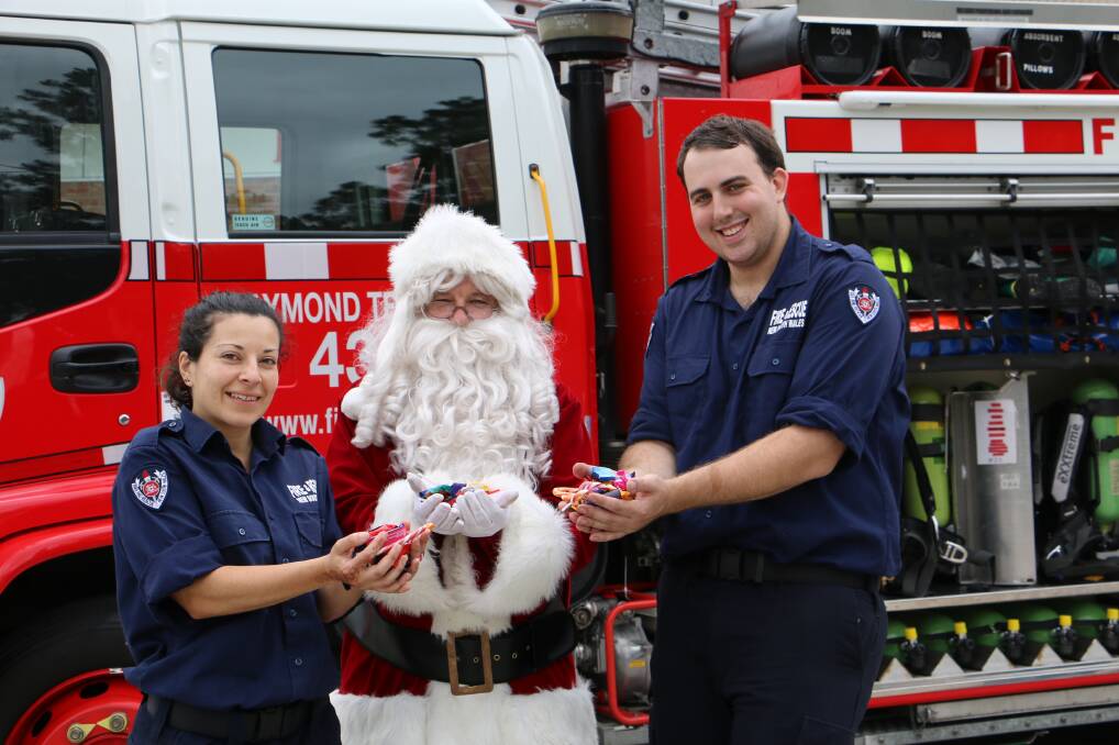 Raymond Terrace Fire and Rescue firefighters Isabel Rios and James Goodliff with Santa.
