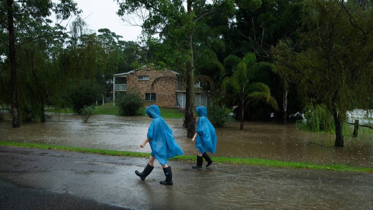 A couple walking along a flooded Swan Street, Raymond Terrace during the March 2021 downpour.