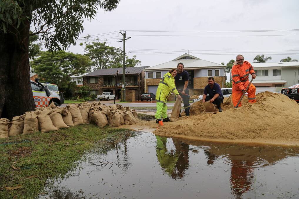 TEAM WORK: Rural Fire Service firefighters Cas Schmitzer (Fingal Bay), Tim Spencer (Anna Bay), Mick Cassar (Soldiers Point) and Tomaree SES member Malcolm Fenn filling up sandbags in Corlette on Monday. Picture: Ellie-Marie Watts