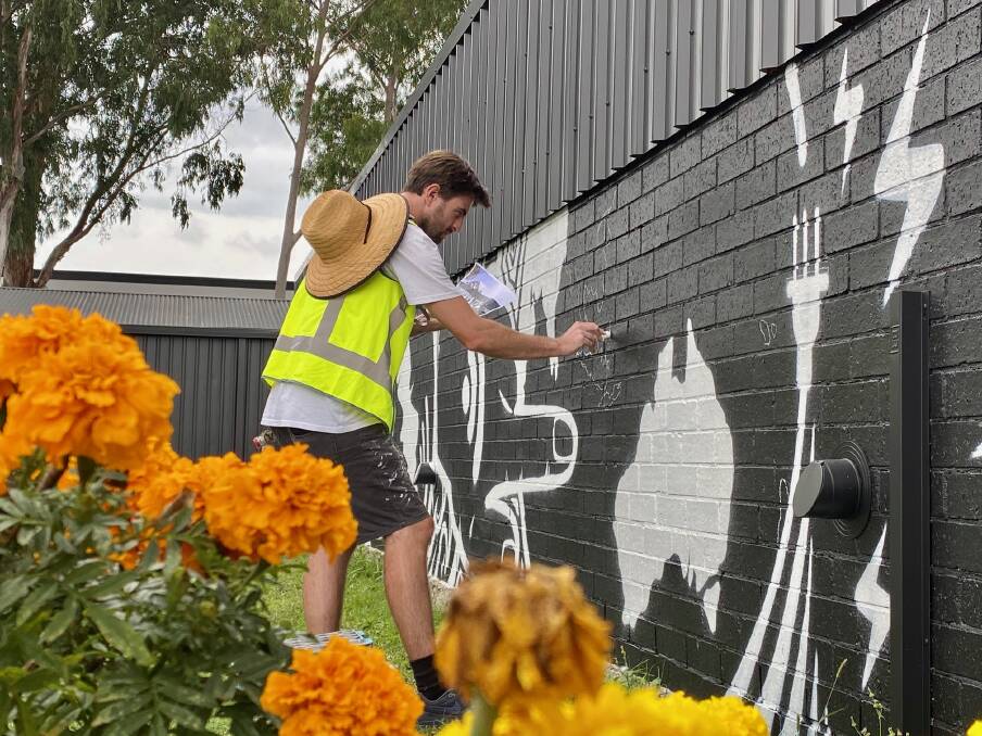  Fishermans Bay street artist Nick Stuart at Raymond Terrace Library on April 9 where he first draw then spray painted a mural to remind youths about the importance of staying connected. 
