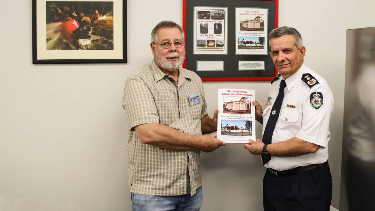 Paul Mulvaney of the Karuah Local History Group presenting a book detailing the history of the Karuah Rural Fire Brigade to NSW Rural Fire Service commissioner Rob Rogers.