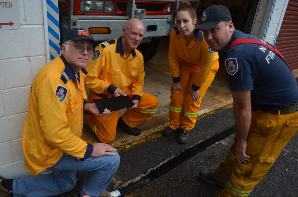 SMASHED: A plastic strip drain with a metal grate, installed to stop flooding, was smashed the first time their eight tonne truck drove over it. Pictured are Jim Semple, acting captain Ken Smee, Holly Martinov and Andy Martinov.